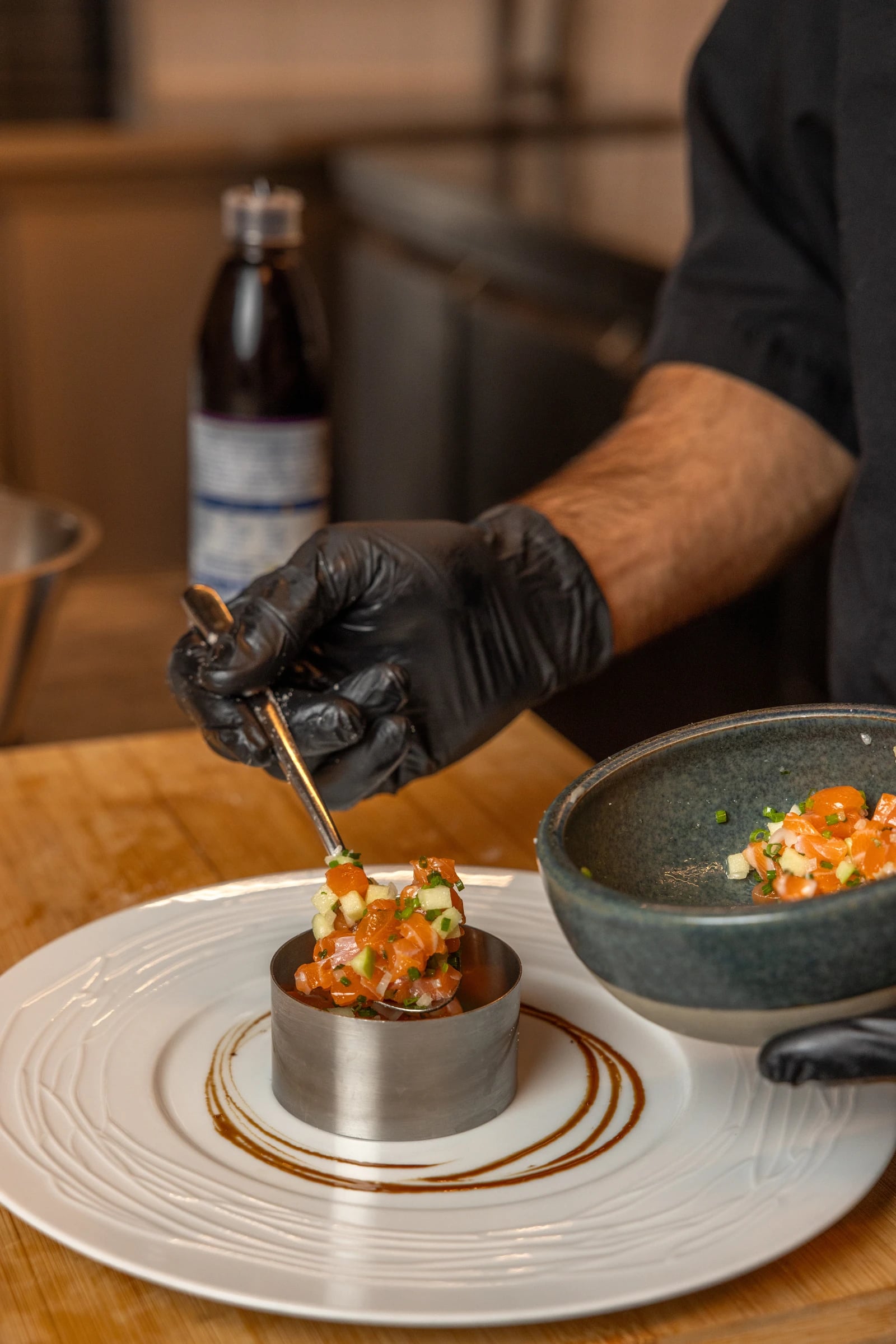 Le chef dresse un tartare de saumon dans la cuisine d’Augusto